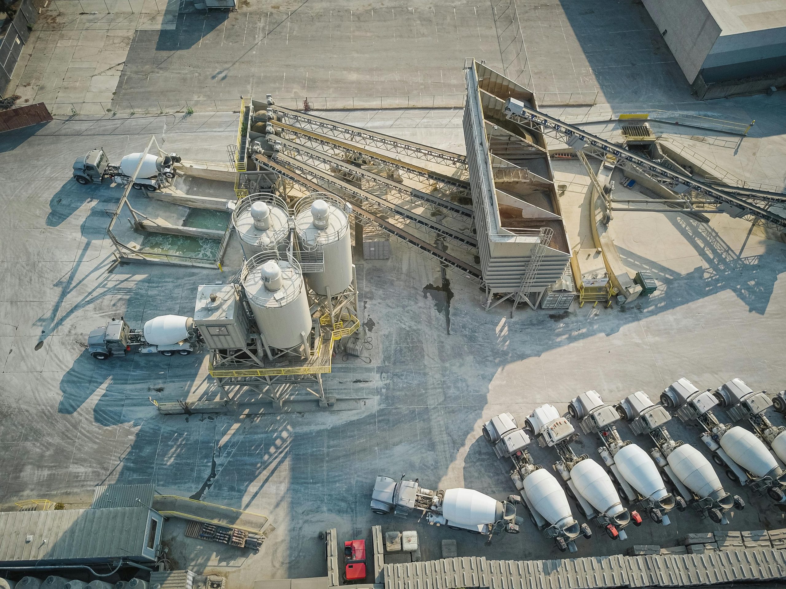 A drone-captured aerial view of an industrial concrete mixing plant with trucks and machinery.